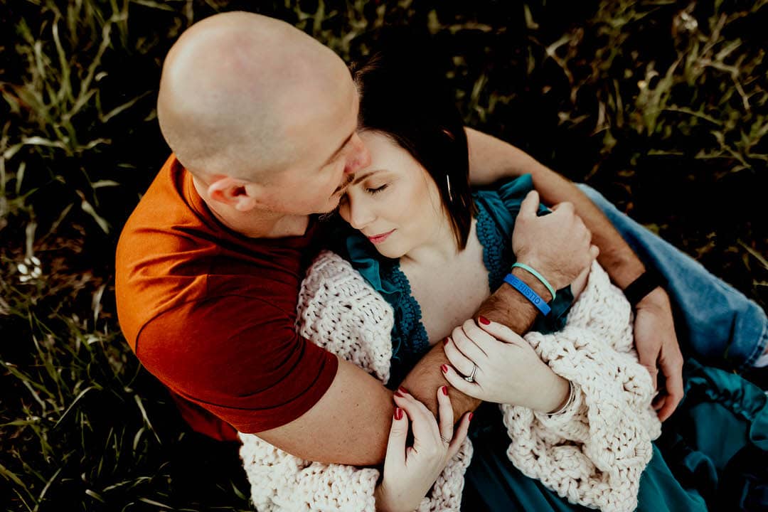 Husband holding wife in arms in a field. day spa Warner Robins