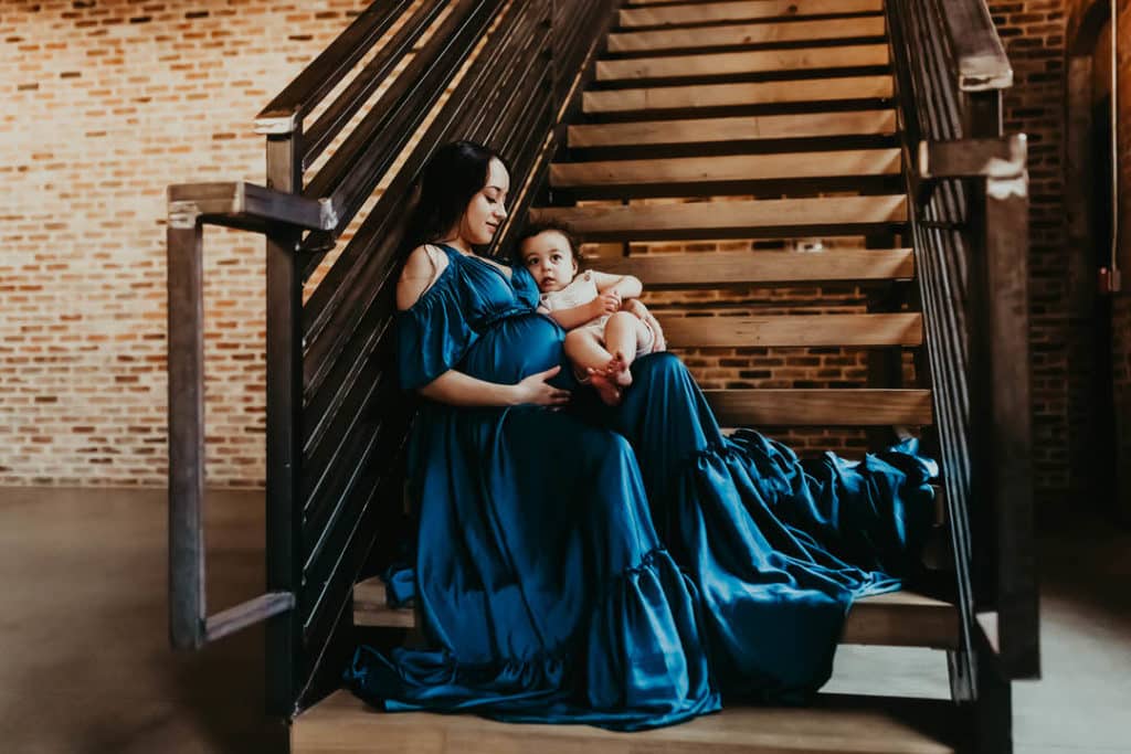 Midwives of Macon GA: Pregnancy, Birth & Women's Care Guide 7 Pregnant mother in a blue dress holding her baby during a maternity photo session in Macon Georgia