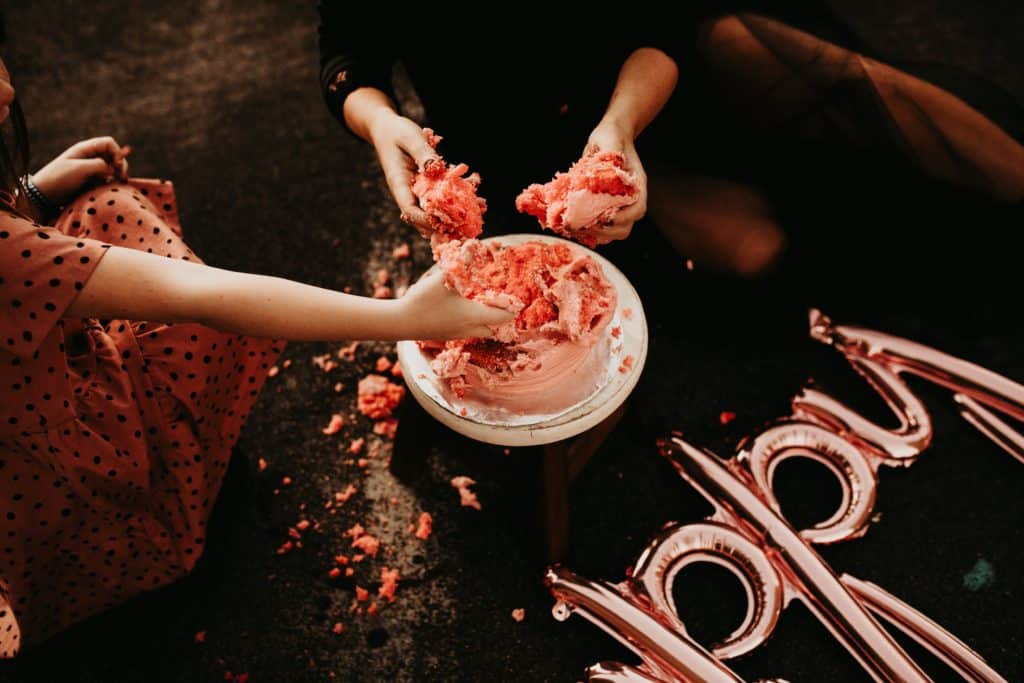 mom and daughter hands smashing a pink cake into their hands