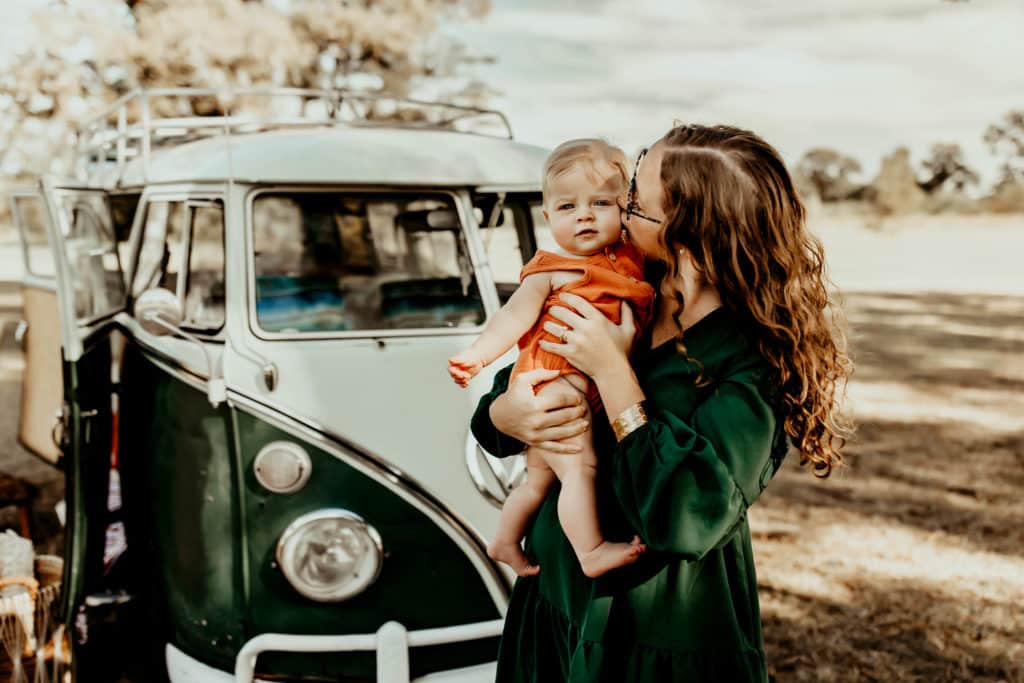 Candid moment captured of mother and son standing in front of a green and white vintage VW van.