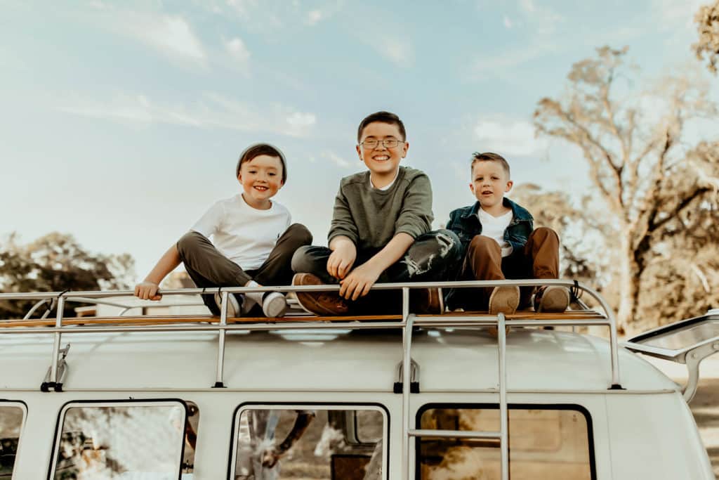 three brothers sitting on the roof of a vintage VW van