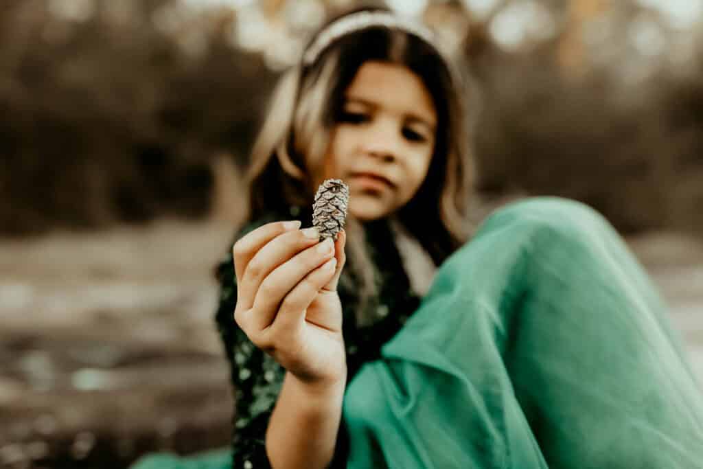 detail of a little girl holding a small pine cone