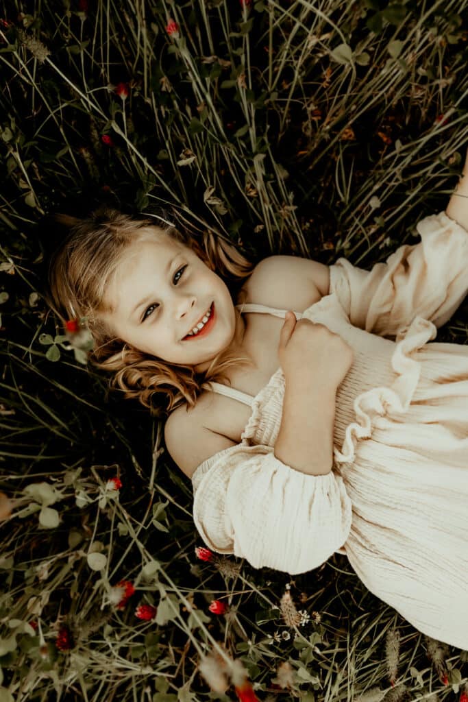 little girl laying in a field of red clovers