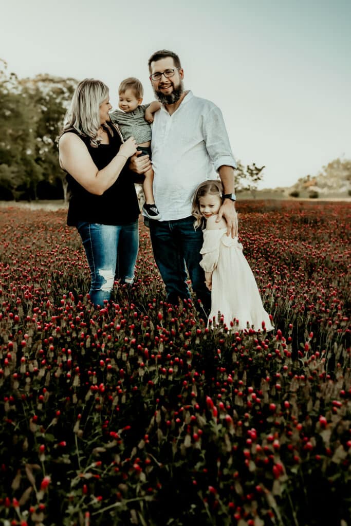 family of 4 standing in a field of recovers in Perry GA captured by Fire Family Photography
