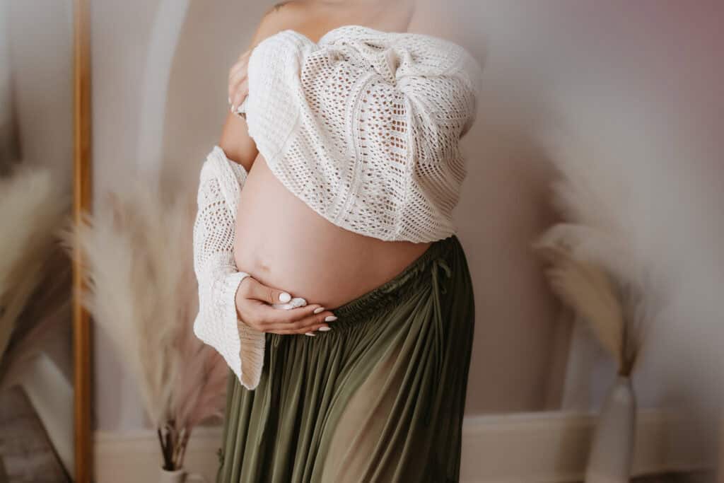 Maternity Session Prep Checklist: What to Wear, What to Bring, and How to Feel Ready 12 Close-up of hands on baby bump with textured knit sweater for maternity photos