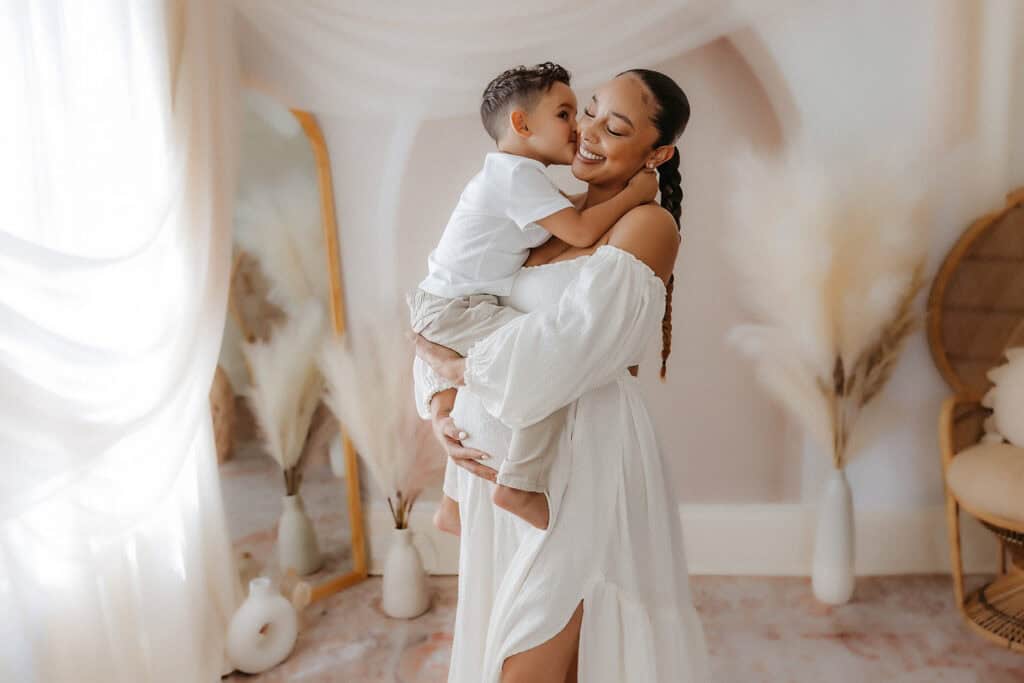 Maternity Session Prep Checklist: What to Wear, What to Bring, and How to Feel Ready 6 Studio maternity family photo with mom holding her toddler in a flowing white dress