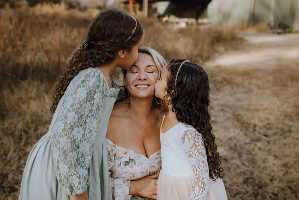 A Cozy Fall Family Session in Perry, GA with the Franklin Family 4 Two girls kissing their mom’s cheeks while she smiles with her eyes closed