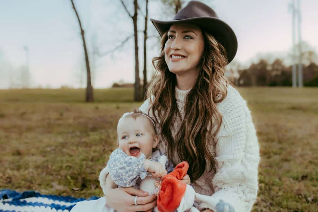 11 Things to Do With Toddlers Near Me in Middle Georgia 3 Smiling mother holding her happy baby while sitting together in a grassy Middle Georgia park.