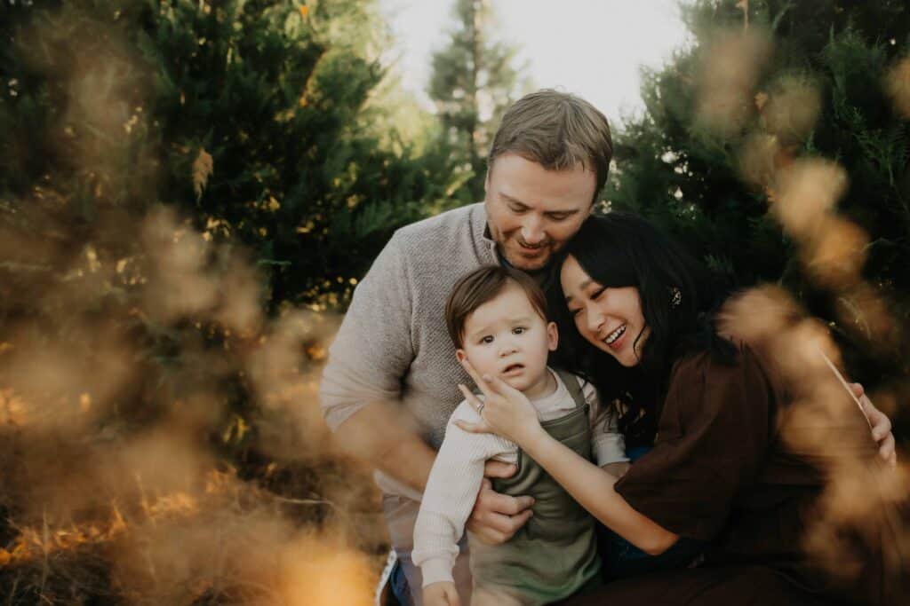 Middle Georgia Christmas Tree Farms: Your 2026 Family Guide 3 Parents cuddling their toddler during family photos at one of the Middle Georgia Christmas Tree Farms