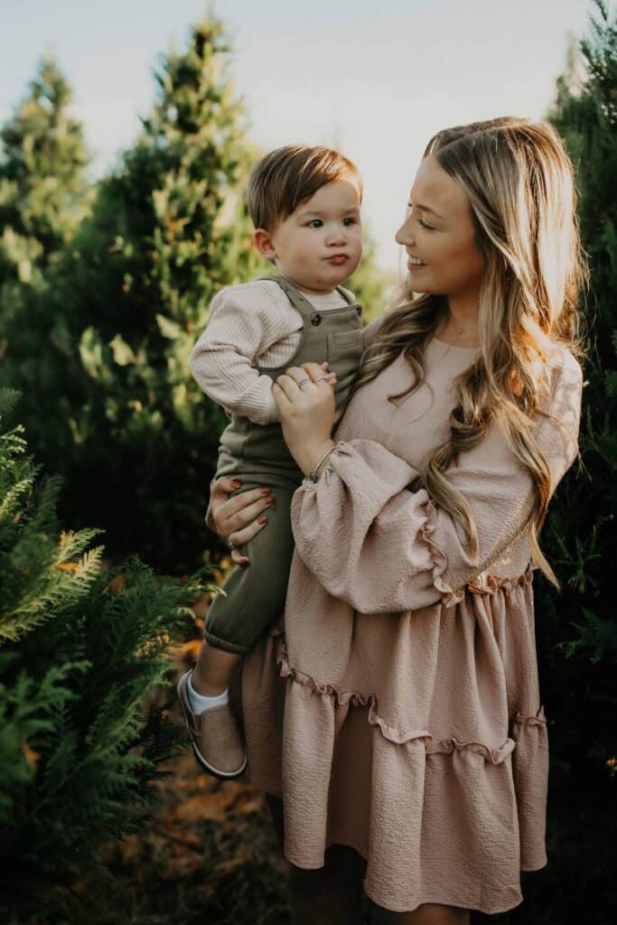 Middle Georgia Christmas Tree Farms: Your 2026 Family Guide 7 Older sister holding her young brother between rows of Christmas trees at a Byron, Georgia tree farm