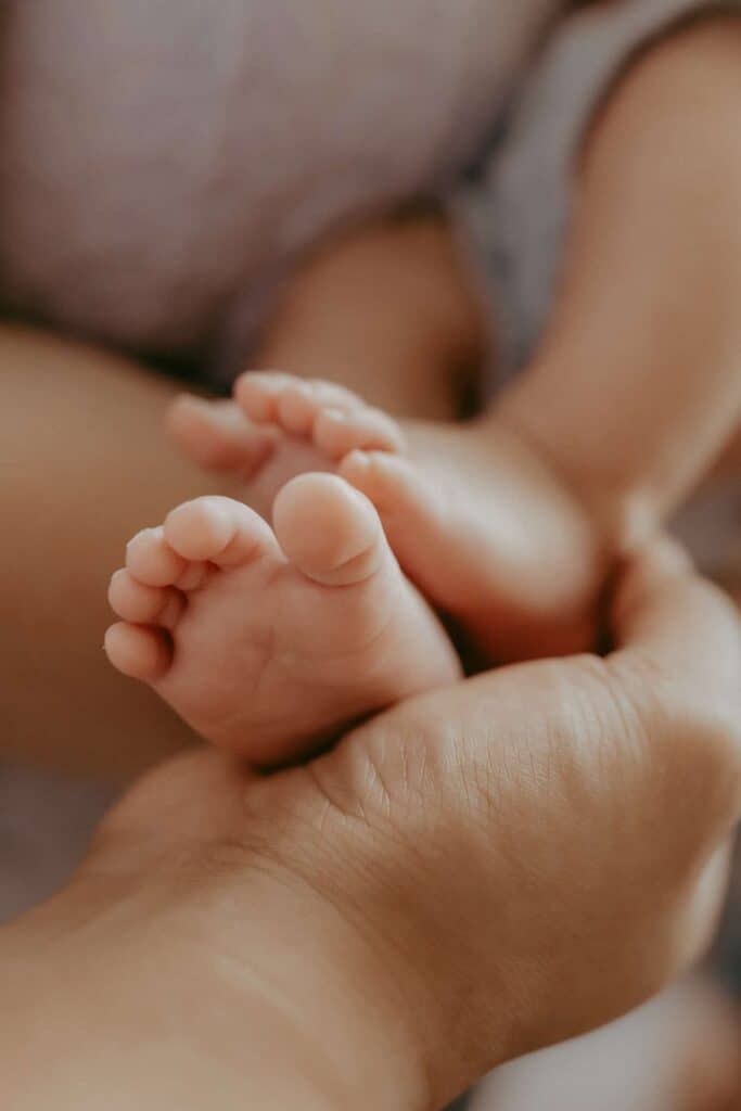 Do Newborn Photos Have to Happen in the First Two Weeks? 8 Close-up of a newborn baby’s tiny feet resting in a parent’s hand.