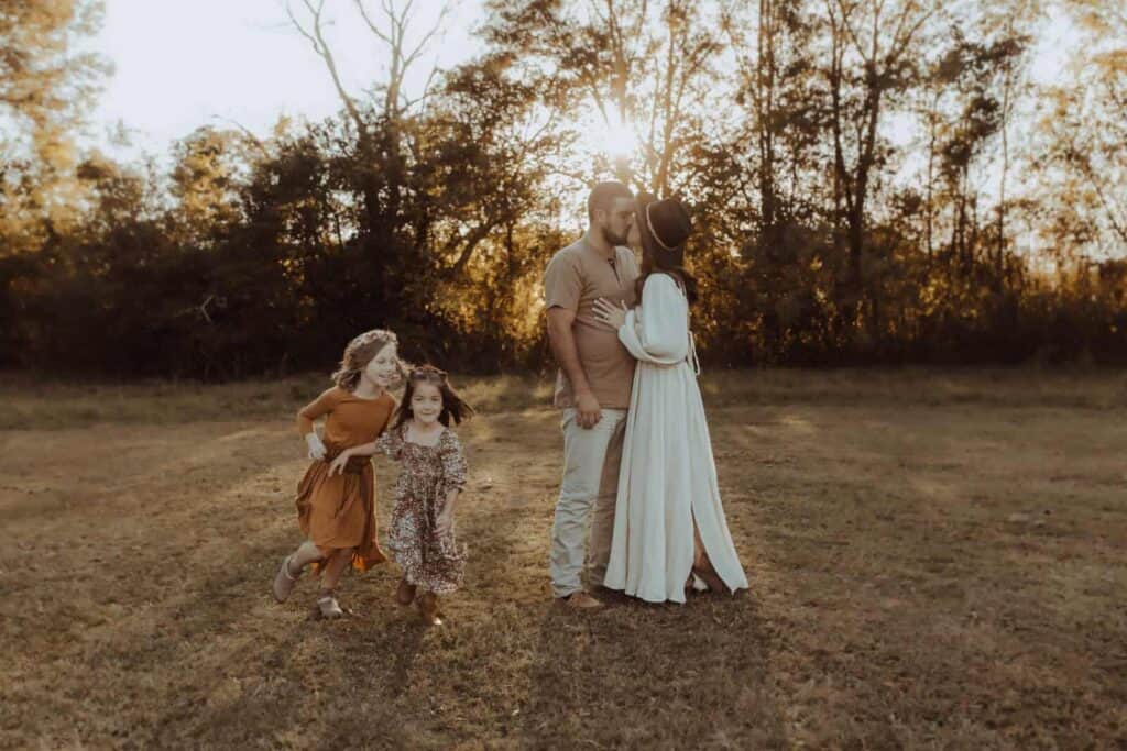 Parents together while their children run and play during fall family photos in Macon GA