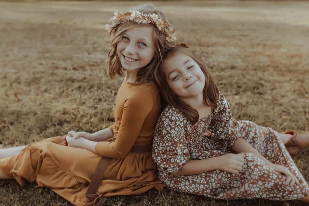 Two sisters smiling together during an outdoor fall family photo session