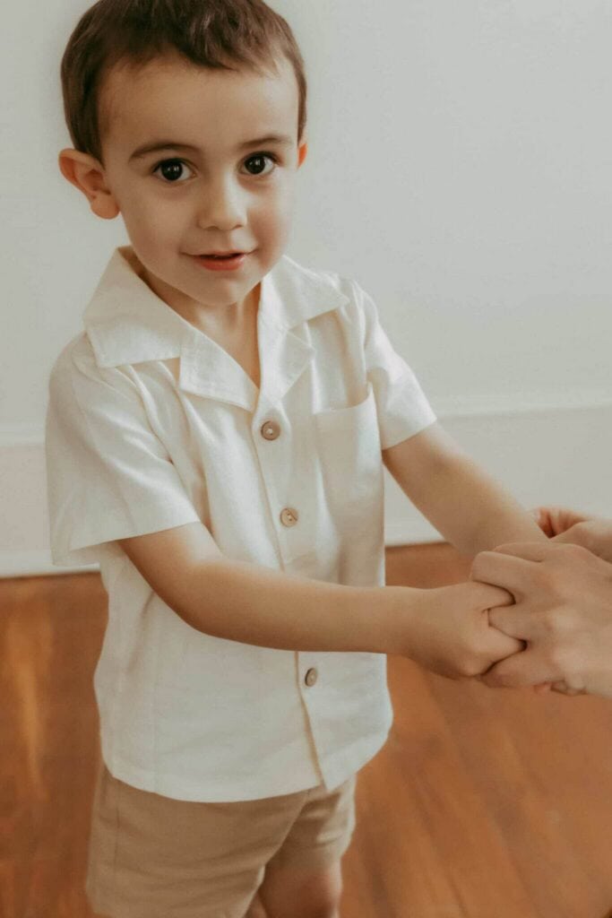 Warner Robins Pediatricians: A Local Guide for Families 5 Young boy smiling and holding his mom’s hands during a studio motherhood session